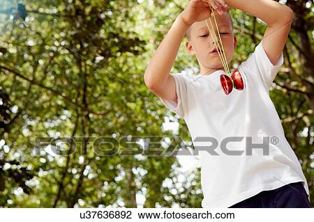 Low angle view of boy playing with yo-yo looking down View Large Photo Image Stock Image - Low angle view of boy playing with yo-yo looking down. Fotosearch