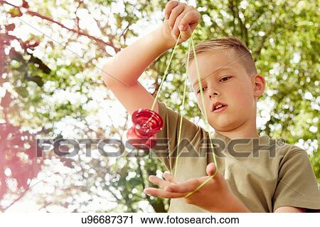 Low angle view of boy playing with yo-yo looking down View Large Photo Image Stock Image - Low angle view of boy playing with yo-yo looking down. Fotosearch