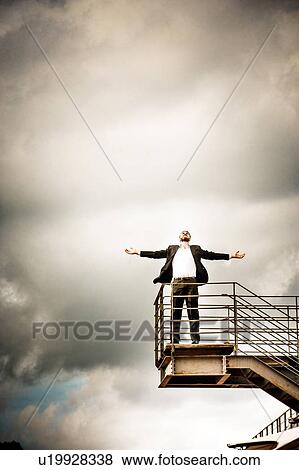 Low angle view of mid adult man on stairs wearing suit, arms open thowing head back View Large Photo Image Stock Photo - Low angle view of mid adult man on stairs wearing suit, arms open thowing head back. Fotosearch