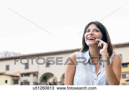Low angle view of young woman talking on cellular phone looking up smiling, Florence, Tuscany, Italy View Large Photo Image Stock Image - Low angle view of young woman talking on cellular phone looking up smiling, Florence, Tuscany, Italy. Fotosearch