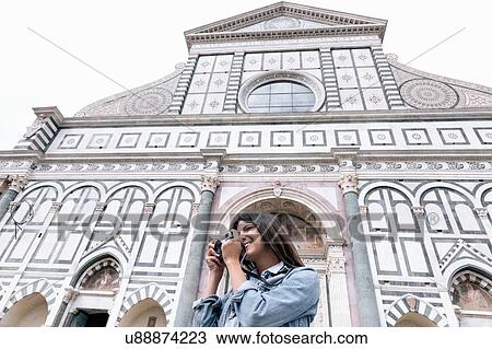 Low angle view of young woman using digital camera in front of church, Piazza Santa Maria Novella, Florence, Tuscany, Italy View Large Photo Image Stock Image - Low angle view of young woman using digital camera in front of church, Piazza Santa Maria Novella, Florence, Tuscany, Italy. Fotosearch