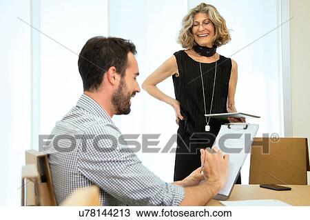 Stock Image - Male and female designers brainstorming at boardroom table. Fotosearch
