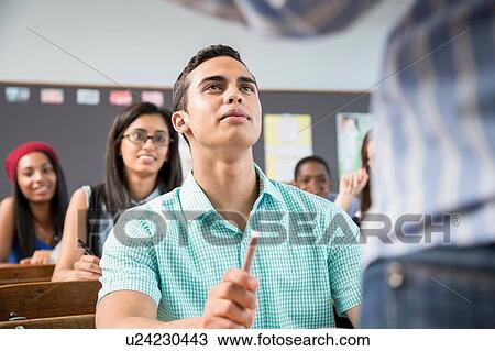Male student listening to teacher in classroom View Large Photo Image Stock Image - Male student listening to teacher in classroom. Fotosearch