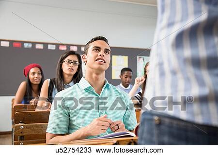 Male student talking to teacher in classroom View Large Photo Image Stock Image - Male student talking to teacher in classroom. Fotosearch