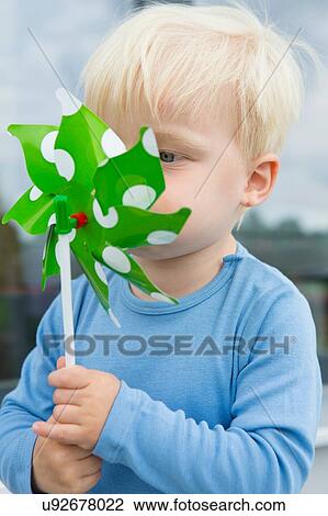 Male toddler blowing pinwheel in front of his face on patio View Large Photo Image Stock Image - Male toddler blowing pinwheel in front of his face on patio. Fotosearch
