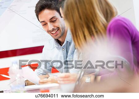 Stock Image - Man and woman sitting together, laughing. Fotosearch