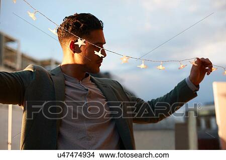 Man handing garden lights for early evening party View Large Photo Image Picture - Man handing garden lights for early evening party. Fotosearch