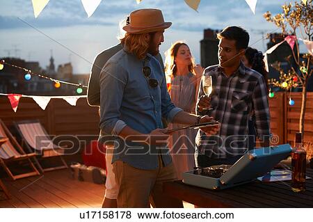 Man putting on music at early evening party View Large Photo Image Stock Photo - Man putting on music at early evening party. Fotosearch