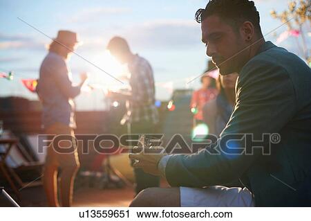 Man sitting alone with drink at early evening party View Large Photo Image Stock Image - Man sitting alone with drink at early evening party. Fotosearch