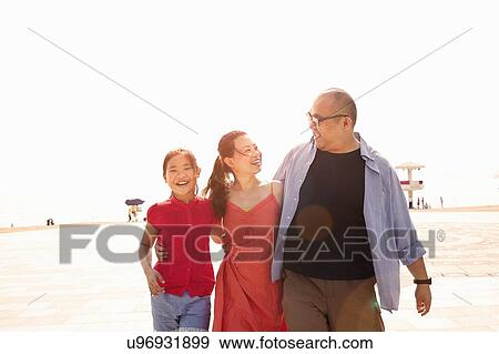 Stock Photo - Mature man strolling on beach with arm around wife and daughter, Zhuhai, Guangdong, China. Fotosearch