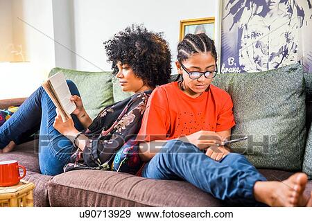 Mature woman and son back to back on living room sofa View Large Photo Image Stock Photo - Mature woman and son back to back on living room sofa. Fotosearch