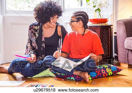 Stock Photo - Mature woman and son doing homework on living room floor. Fotosearch