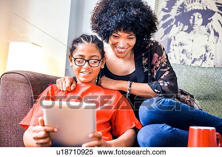 Mature woman and son reading digital tablet in living room View Large Photo Image Stock Photography - Mature woman and son reading digital tablet in living room. Fotosearch