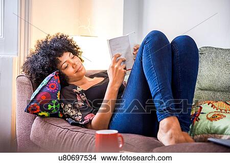 Mature woman reclining on sofa reading book View Large Photo Image Picture - Mature woman reclining on sofa reading book. Fotosearch