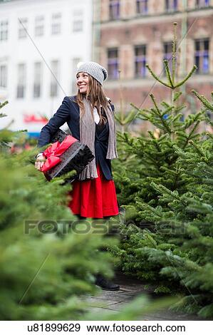 Mature woman with Christmas gift among Christmas trees View Large Photo Image Stock Photo - Mature woman with Christmas gift among Christmas trees. Fotosearch