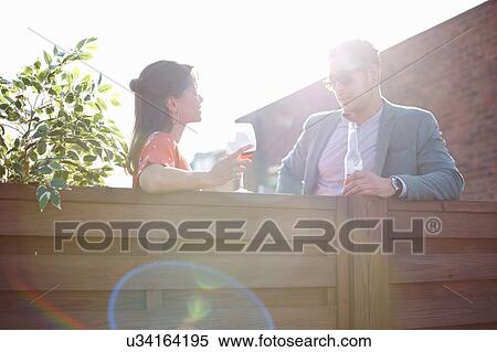 Mid adult couple chatting at fence at rooftop party View Large Photo Image Stock Photography - Mid adult couple chatting at fence at rooftop party. Fotosearch