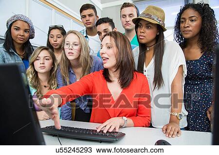Mid adult female teacher explaining on computer to high school students View Large Photo Image Stock Image - Mid adult female teacher explaining on computer to high school students. Fotosearch