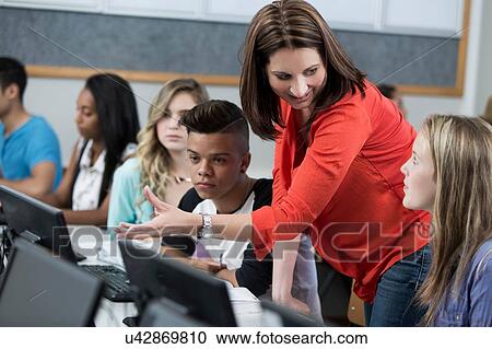 Mid adult female teacher explaining to high school students in class View Large Photo Image Stock Image - Mid adult female teacher explaining to high school students in class. Fotosearch