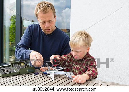 Mid adult man and son preparing toy airplane on patio table View Large Photo Image Picture - Mid adult man and son preparing toy airplane on patio table. Fotosearch