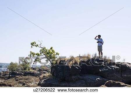 Mid adult man looking out from rocks, near Victoria Falls, Zambia View Large Photo Image Stock Image - Mid adult man looking out from rocks, near Victoria Falls, Zambia. Fotosearch