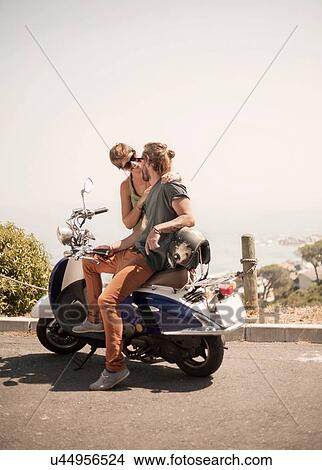 Mid adult man sitting on moped, looking at young woman beside him View Large Photo Image Picture - Mid adult man sitting on moped, looking at young woman beside him. Fotosearch