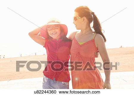 Stock Image - Mid adult woman and daughter at beach, Zhuhai, Guangdong, China. Fotosearch