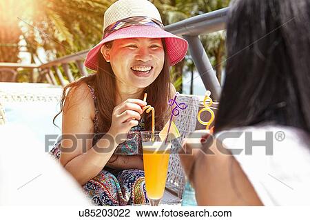 Stock Image - Mid adult woman and daughter at beach cafe, Zhuhai, Guangdong, China. Fotosearch