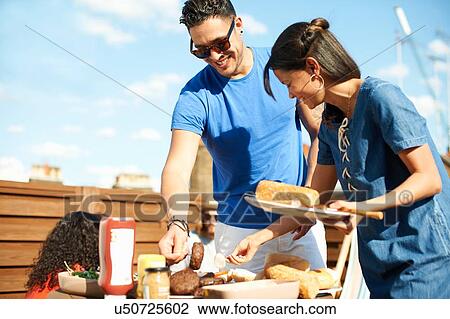 Mid adult woman selecting food at rooftop party View Large Photo Image Stock Image - Mid adult woman selecting food at rooftop party. Fotosearch