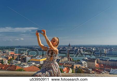 Stock Image - Mid adult woman taking self portrait using smartphone, Budapest, Hungary. Fotosearch