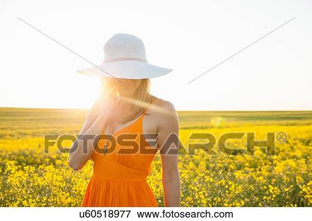 Mid adult woman using mobile phone in canola field wearing sunhat looking down View Large Photo Image Stock Photo - Mid adult woman using mobile phone in canola field wearing sunhat looking down. Fotosearch