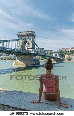 Stock Image - Mid adult woman watching The Chain Bridge over the Danube, Budapest, Hungary. Fotosearch