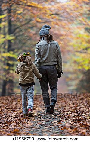Stock Image - Mother and daughter walking in autumn forest. Fotosearch