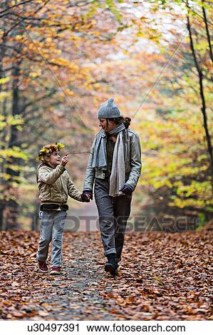 Stock Image - Mother and daughter walking in autumn forest. Fotosearch