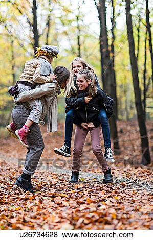 Mother and daughters playing piggyback ride in autumn forest View Large Photo Image Stock Photo - Mother and daughters playing piggyback ride in autumn forest. Fotosearch