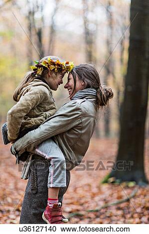 Mother carrying daughter in autumn forest View Large Photo Image Stock Image - Mother carrying daughter in autumn forest. Fotosearch