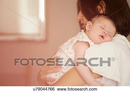 Stock Photograph - Mother carrying sleeping baby. Fotosearch