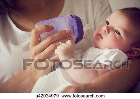 Mother feeding baby in arms View Large Photo Image Stock Photo - Mother feeding baby in arms. Fotosearch