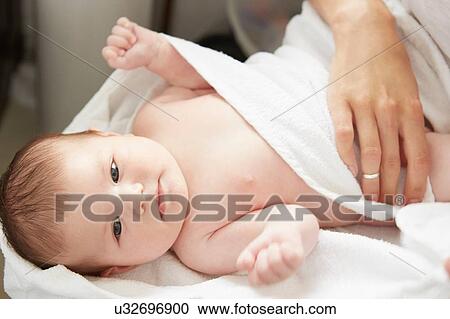 Stock Image - Mother wrapping baby with blanket in bed. Fotosearch