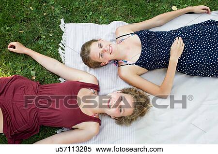 Overhead portrait of two teenage girls lying on picnic blanket in park View Large Photo Image Stock Photography - Overhead portrait of two teenage girls lying on picnic blanket in park. Fotosearch