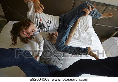 Stock Photo - Overhead view of father and daughter playing on bed. Fotosearch