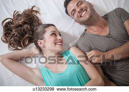 Overhead view of young couple lying on bed in hotel View Large Photo Image Stock Photo - Overhead view of young couple lying on bed in hotel. Fotosearch
