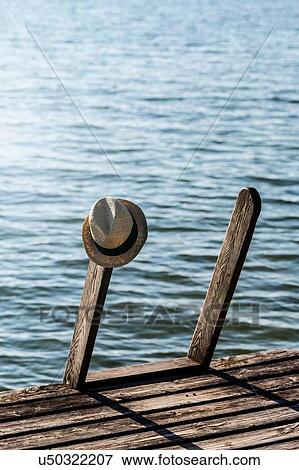 Panama hat hanging on steps of wood pier next to lake View Large Photo Image Stock Photo - Panama hat hanging on steps of wood pier next to lake. Fotosearch