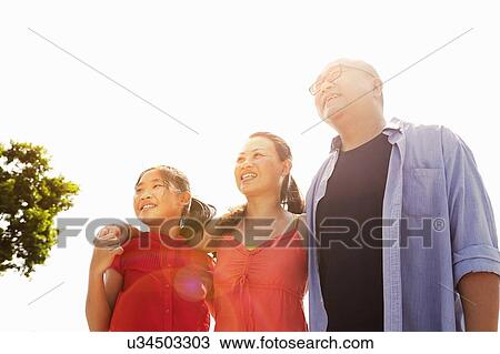 Stock Image - Parents and daughter strolling in sunlight. Fotosearch