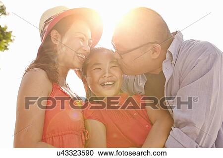 Parents kissing daughter on cheek in sunlight View Large Photo Image Stock Image - Parents kissing daughter on cheek in sunlight. Fotosearch