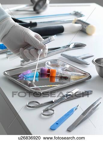 Stock Image - Pathologist taking a DNA sample for analysis during a autopsy. Fotosearch