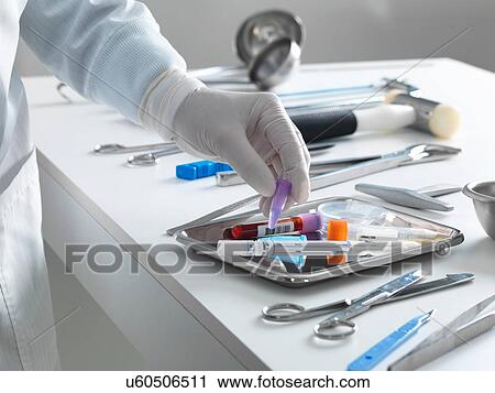 Stock Image - Pathologist taking a sample for analysis during a autopsy. Fotosearch