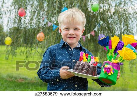 Portrait of boy carrying birthday cake and paper flowers in garden View Large Photo Image Stock Photo - Portrait of boy carrying birthday cake and paper flowers in garden. Fotosearch