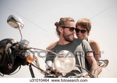 Picture - Portrait of couple sitting on moped. Fotosearch
