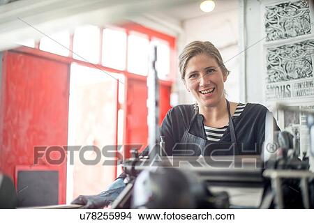 Picture - Portrait of female printer with traditional letterpress print machine in workshop. Fotosearch