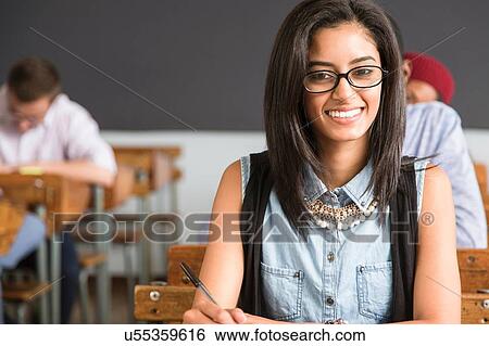 Portrait of female student, sitting at desk in classroom, smiling View Large Photo Image Stock Photograph - Portrait of female student, sitting at desk in classroom, smiling. Fotosearch